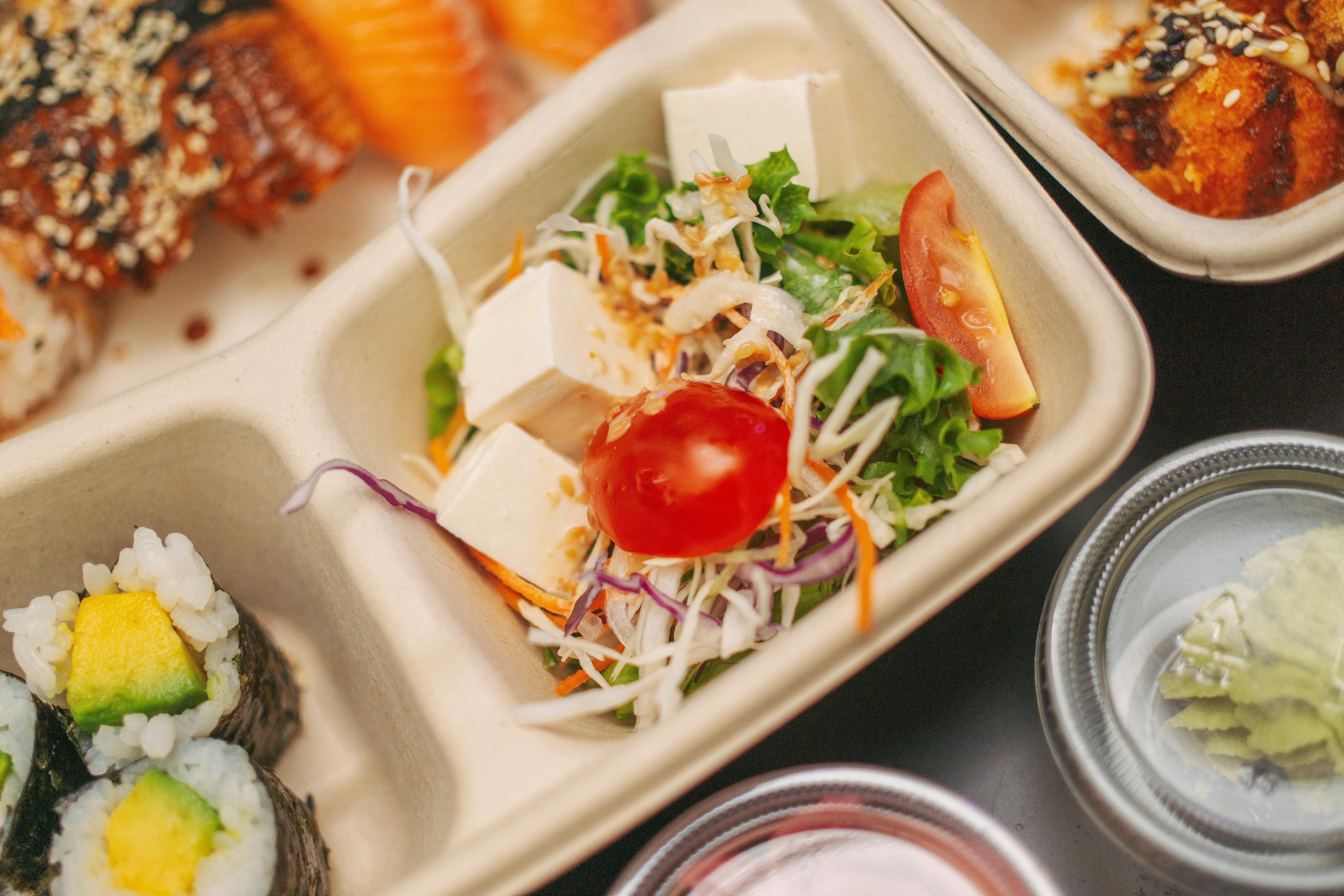 Delicious tofu salad and sushi presented in an elegant bento box for a gourmet meal.