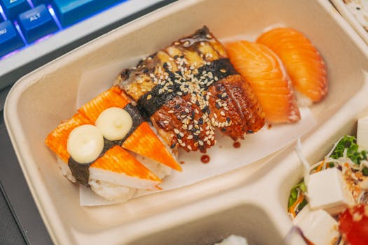 Mouthwatering sushi platter featuring salmon, eel, and tofu with sesame seeds on a tray.