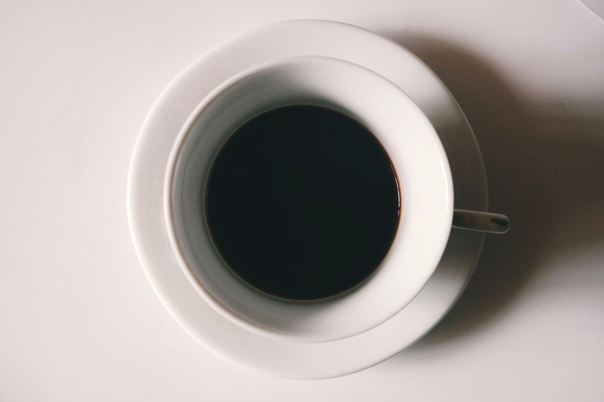 Clean minimalist shot of a black coffee cup on a white table, creating a serene ambiance.
