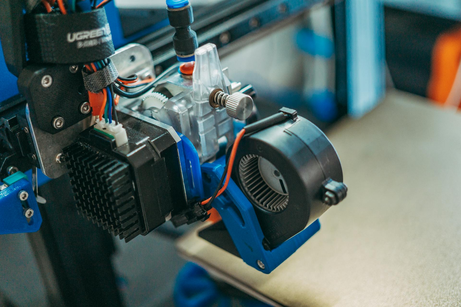 Detailed view of 3D printer parts showing wires and equipment in a workshop setting.