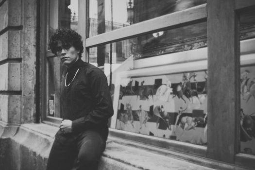 Black and white portrait of a man posing by a glass window in Ciudad de México.