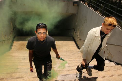 Free Two young adults in an urban setting with smoke grenades, expressing modern street style. Stock Photo