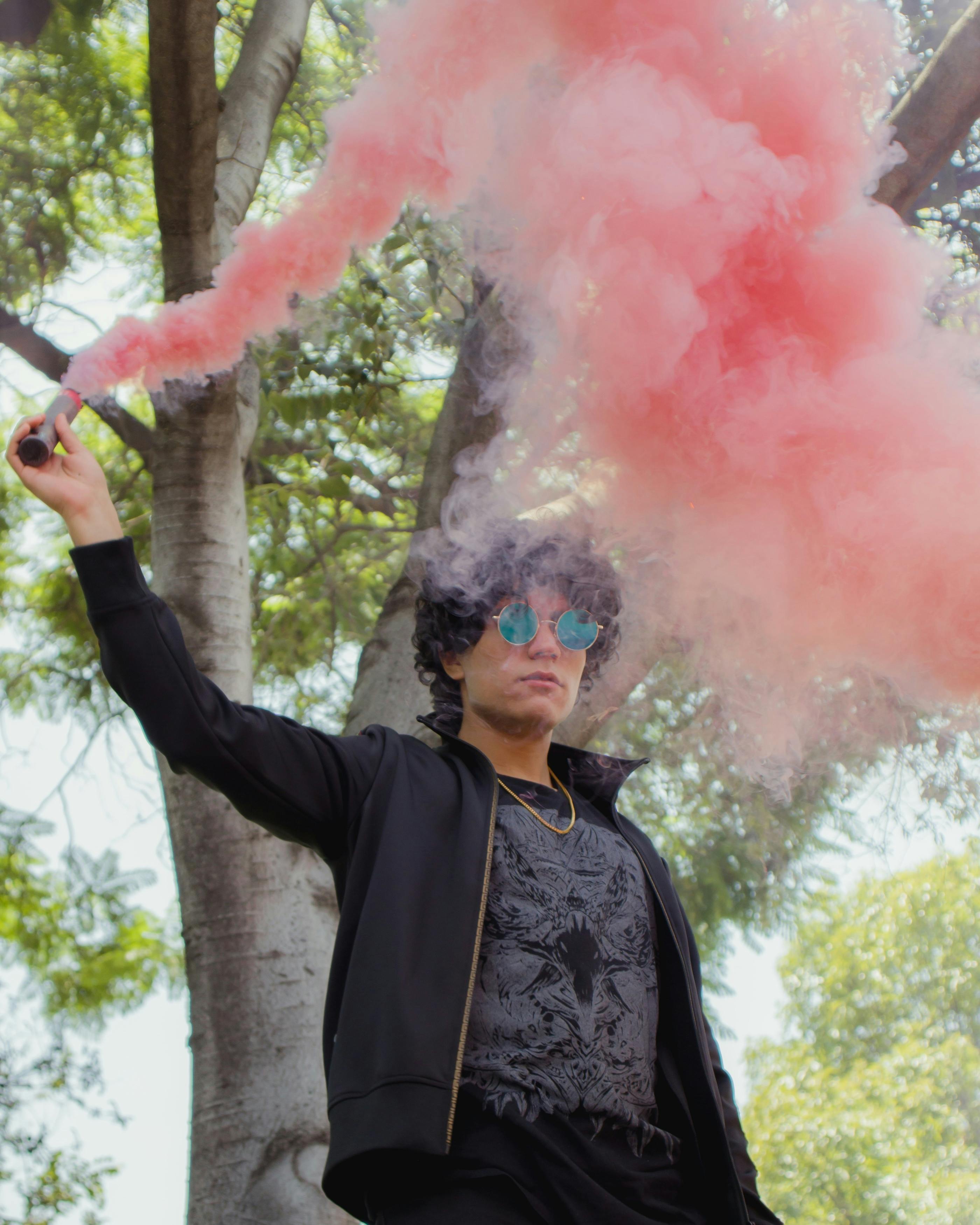 woman in black jacket holding pink smoke