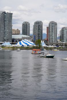 Scenic view of Vancouver's skyline with boats on the water and distinctive blue and white tents.