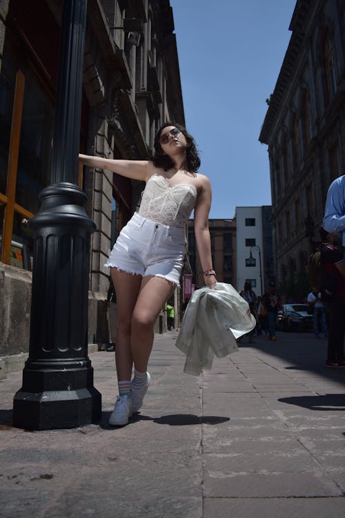 Woman in White Sleeveless Dress Standing on Sidewalk