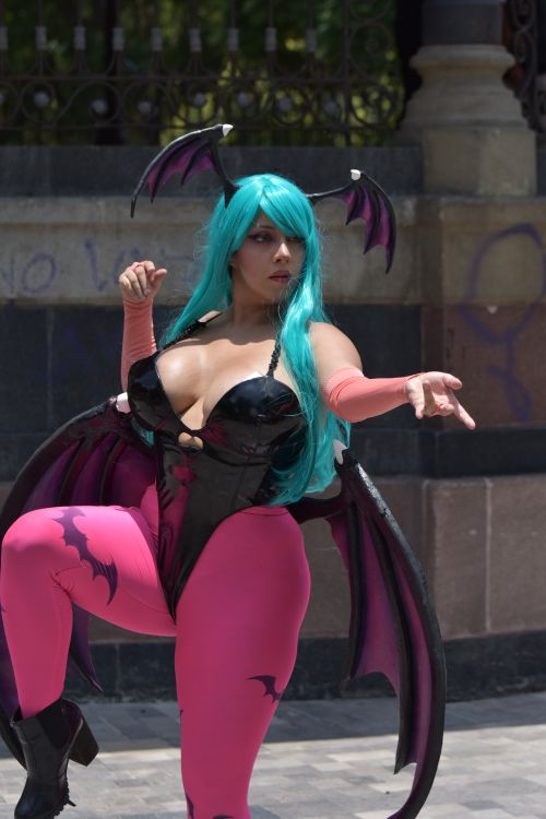 Free Cosplayer showcases vibrant costume with bat wings at outdoor festival. Stock Photo