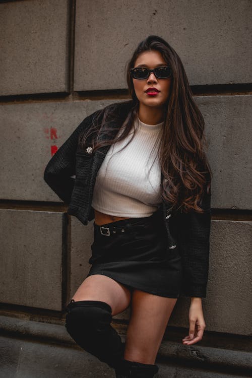 Woman in Black Jacket and Skirt Standing Against a Wall