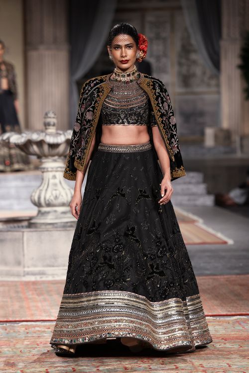 Free Model in ornate black lehenga and cape on a fashion show runway. Stock Photo