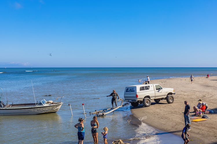 A Person Standing On Trailer Pulling A Boat On Body Of Water