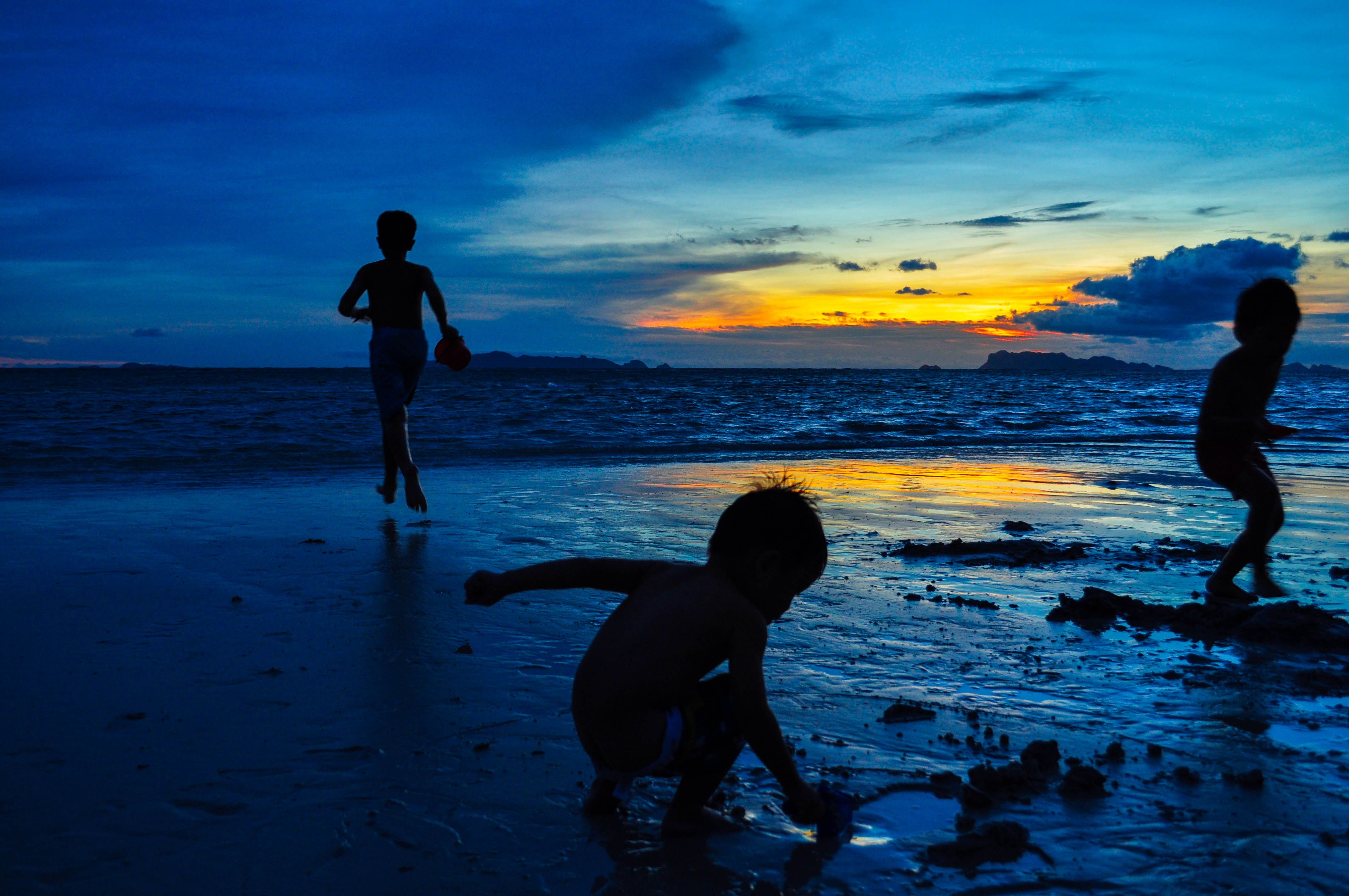 Silhouetted children enjoying a vibrant Koh Samui beach at sunset. Silhouetted children enjoying a vibrant Koh Samui beach at sunset.
