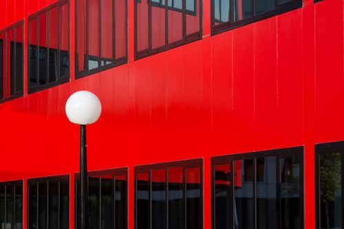 Free Striking red building facade featuring glass windows and a sleek white lamp post. Stock Photo