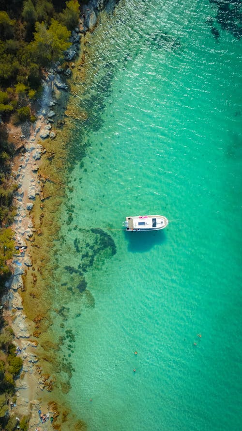 Aerial View of a Boat on the Water Near Rocky Shore