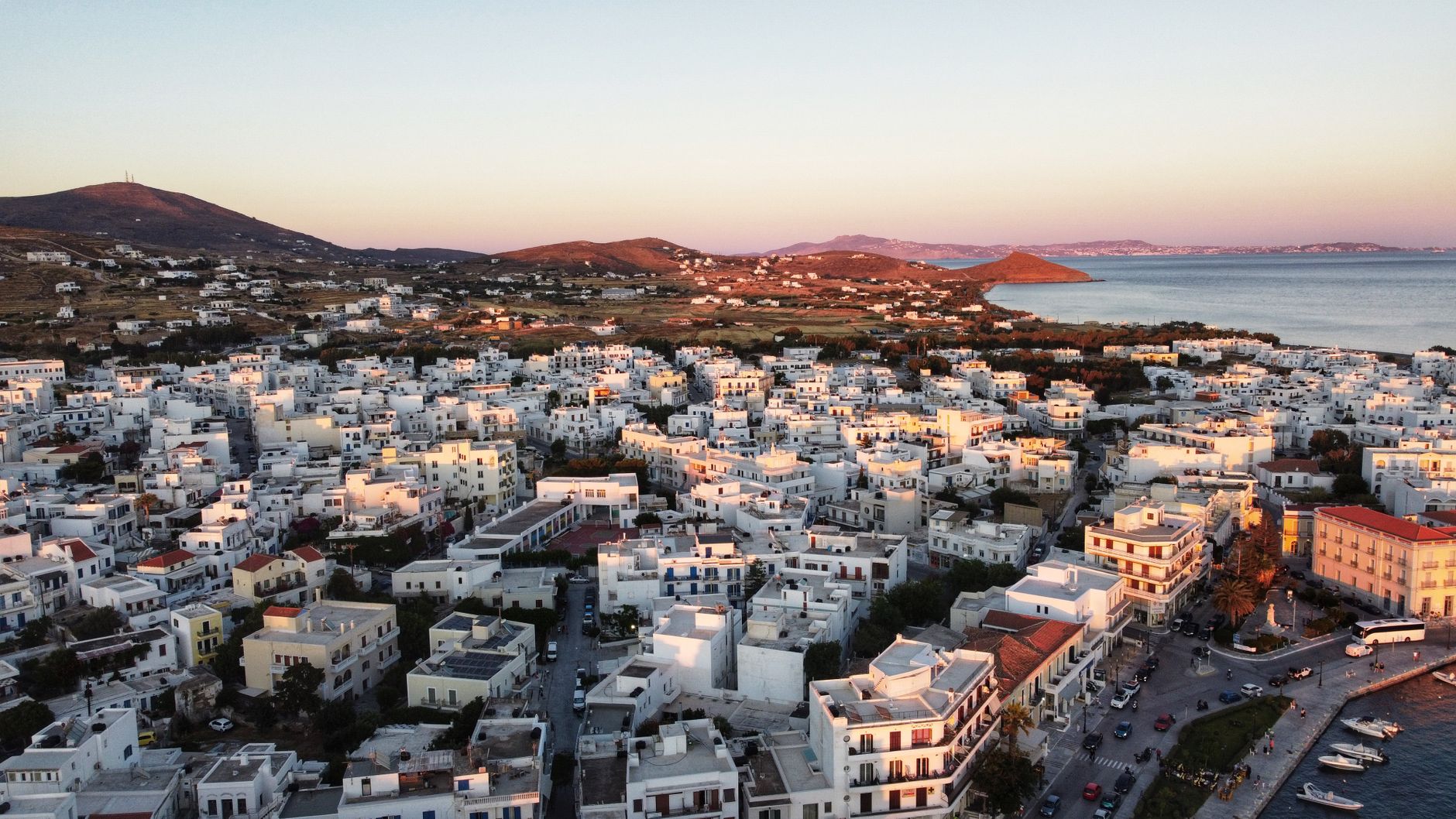 Tinos town and its harbour at sunset, seen from above.