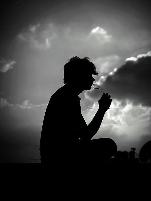 Free A man silhouetted against a dramatic sky, creating a contemplative atmosphere. Stock Photo