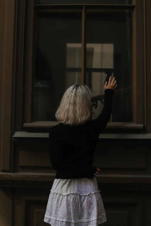Free A Woman Standing by a Window Stock Photo
