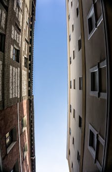 Low-angle shot of adjacent modern buildings framing a clear blue sky.