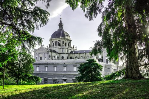 Free View of a historic cathedral through lush greenery and trees, highlighting architectural elegance. Stock Photo