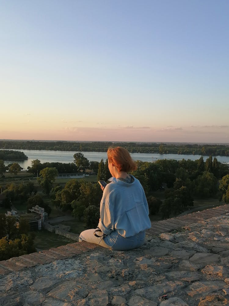 Redhead Young Woman With Phone Sitting On Edge