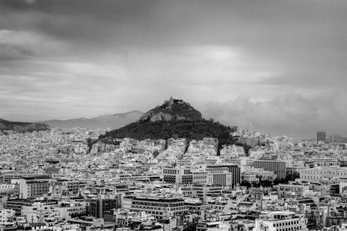Grayscale Photography of City Buildings Near Mountain
