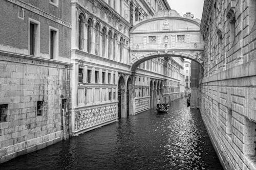 Grayscale Photo of a Person Standing in Gondola Sailing on Grand Canal