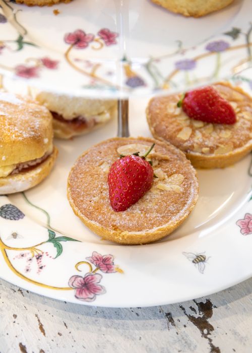 Free Close-up of Bakewell tarts with strawberries served on a floral-patterned plate, highlighting traditional dessert artistry. Stock Photo
