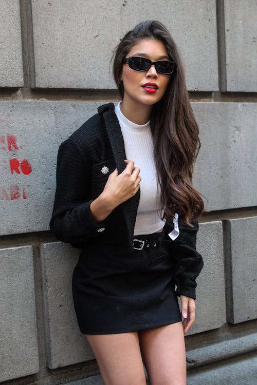 Woman in Black Jacket and Skirt Leaning on the Concrete Wall