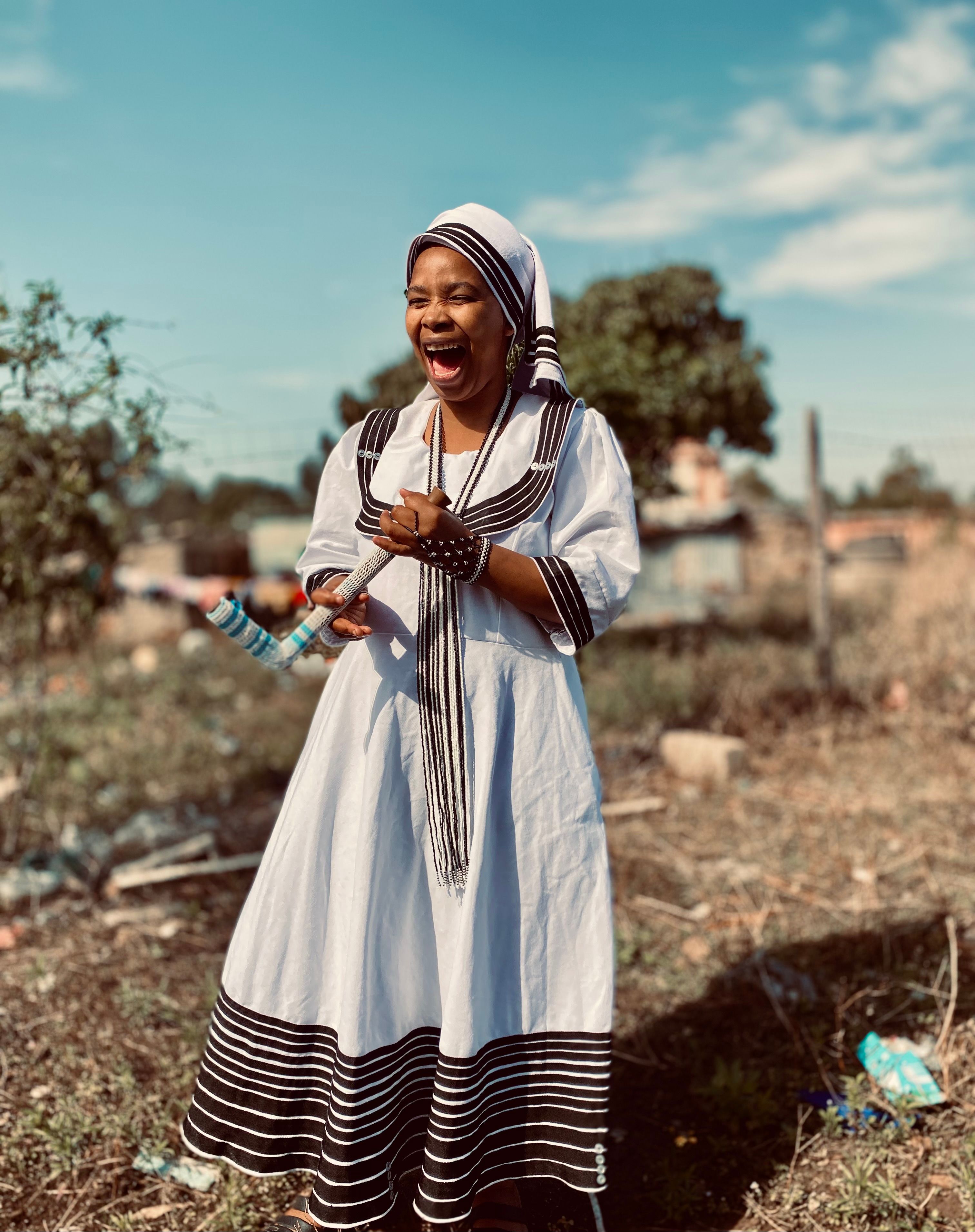 A woman in traditional attire enjoying a moment outdoors with a vibrant expression.
