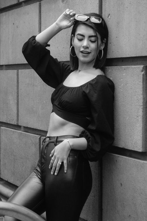 Free Fashionable young woman in a monochrome portrait, leaning against a wall and smiling. Stock Photo