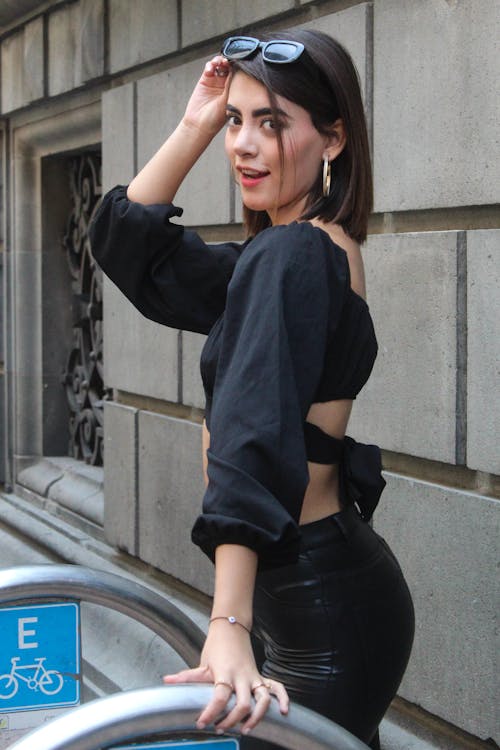 A Woman in Black Crop Top and Leather Pants is Standing Near the Wall