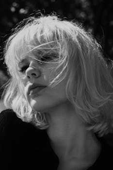 Artistic black and white portrait of a woman with blonde hair outdoors.