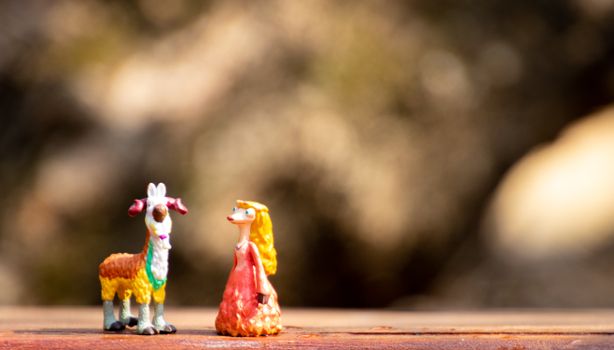 Playful miniature goat and whimsical character figurines on a rustic surface.