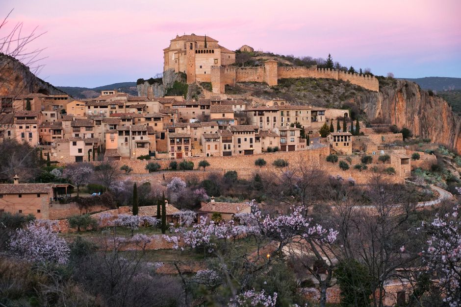 Encantadora vista del atardecer de Alquézar con su histórica fortificación en la cima de la colina y cerezos en flor.