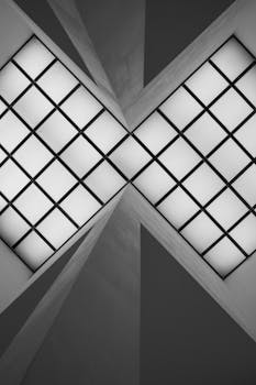 Black and white photo of a geometric ceiling pattern highlighting symmetry and minimalism.