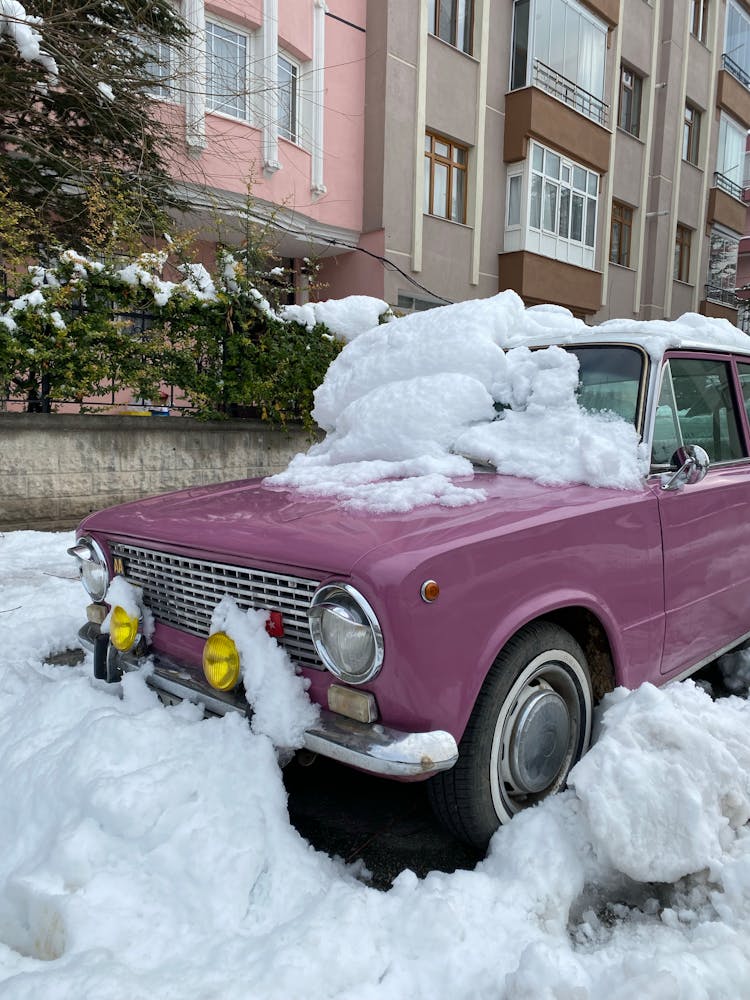 Pink Vintage Car Parked On Street Sidewalk Covered With Snow