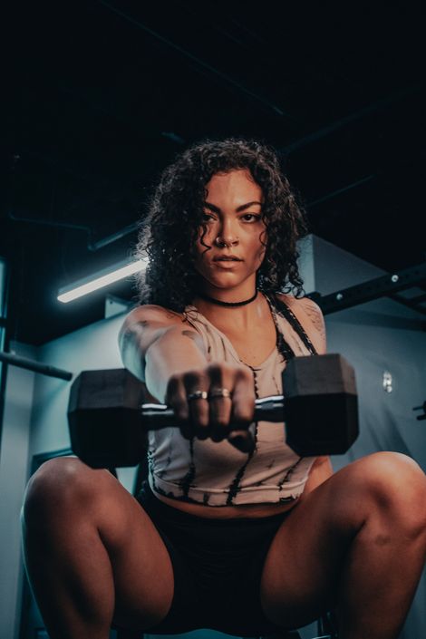 Woman lifting a dumbbell in a dim gym — Joshua Brown on Pexels