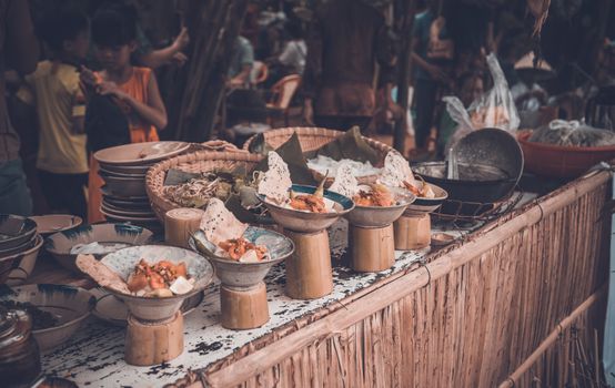 Vibrant street food market with various dishes displayed in unique bowls and plates.