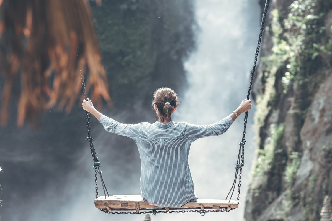 Free Woman Riding Big Swing in Front of Waterfalls Stock Photo