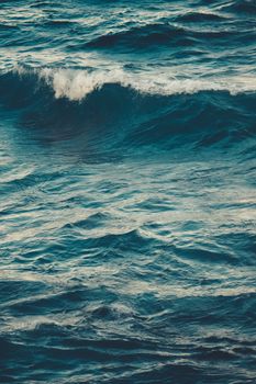 Vibrant ocean waves rolling on a windy day, captured in a vertical shot. Perfect for nature themes.
