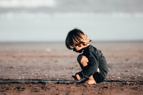 Free Young boy explores the sand on a sunny beach, capturing the essence of childhood play. Stock Photo