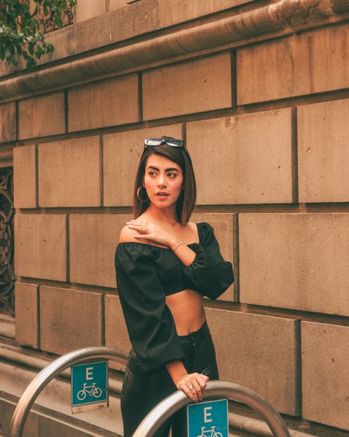 Free Young adult woman in fashionable outfit poses confidently outdoors with sunglasses. Stock Photo