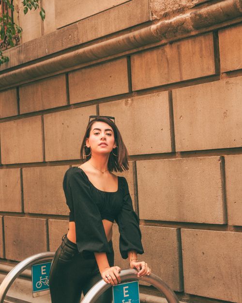 Free Chic woman poses confidently against a rustic wall, showcasing fashion style. Stock Photo