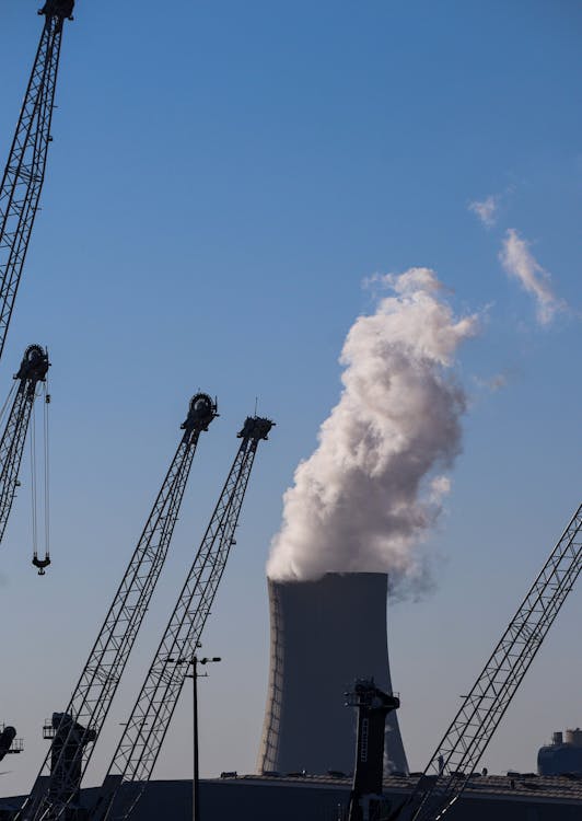 Cranes and Dense Smoke Coming Out of a Large Chimney 