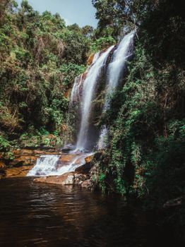 A breathtaking waterfall cascades through a vibrant, green forest creating a tranquil scene.