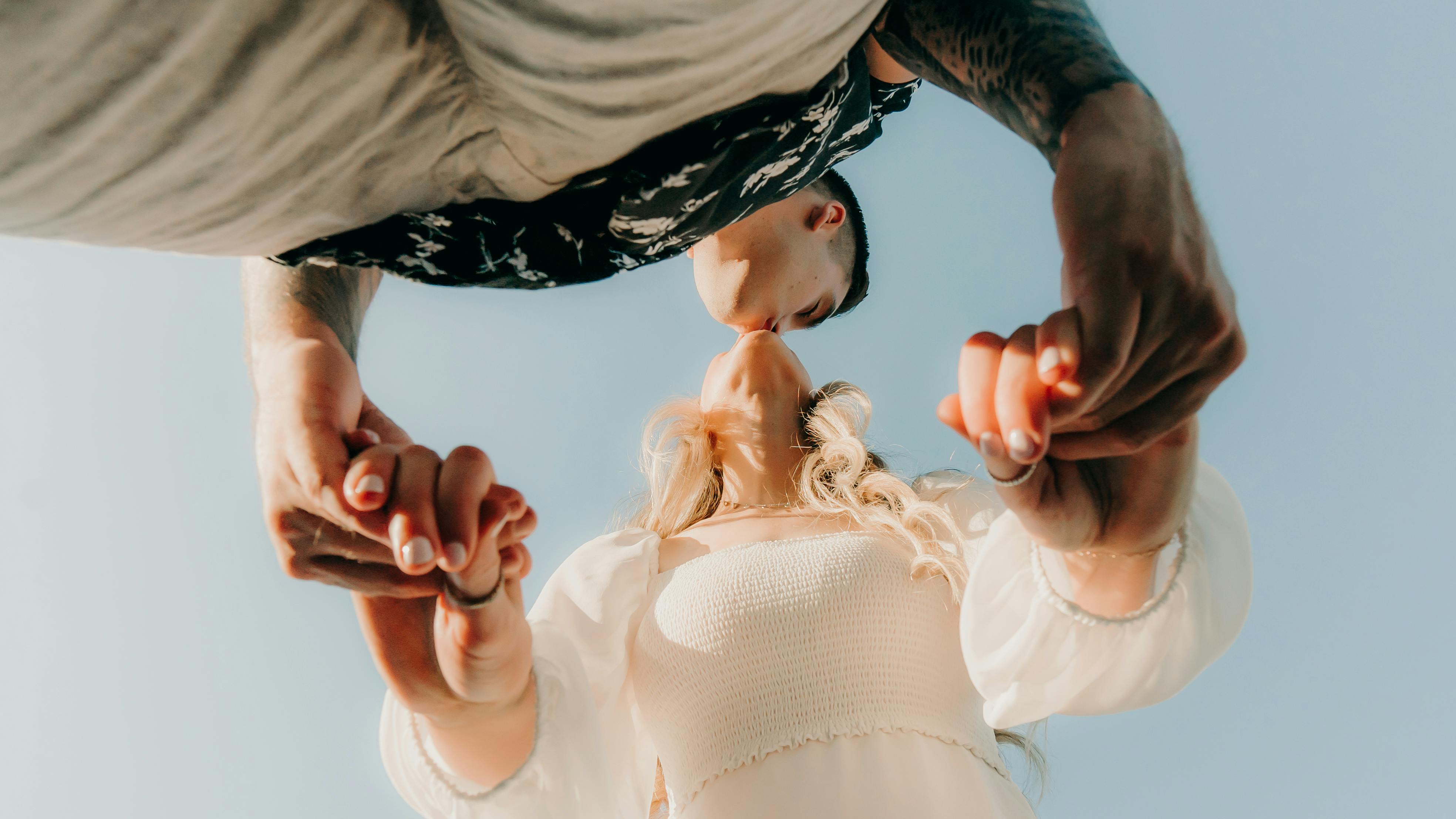 woman in white shirt holding hands and kissing with man