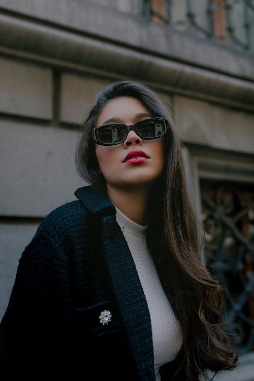 Free Stylish woman with long hair and sunglasses posing in Mexico City backdrop. Stock Photo