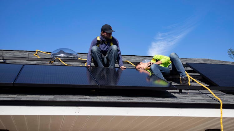 Men Installing Solar Panels On A Roof