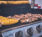 Close-up of sizzling chicken and corn on a barbecue grill, perfect for summer cookouts.