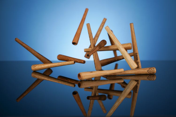 A Set Of Brown Wooden Sticks Falling On Glass Surface