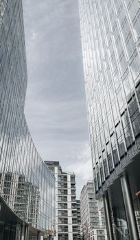 Vertical view of modern skyscrapers in Warsaw with glass facades reflecting the sky.