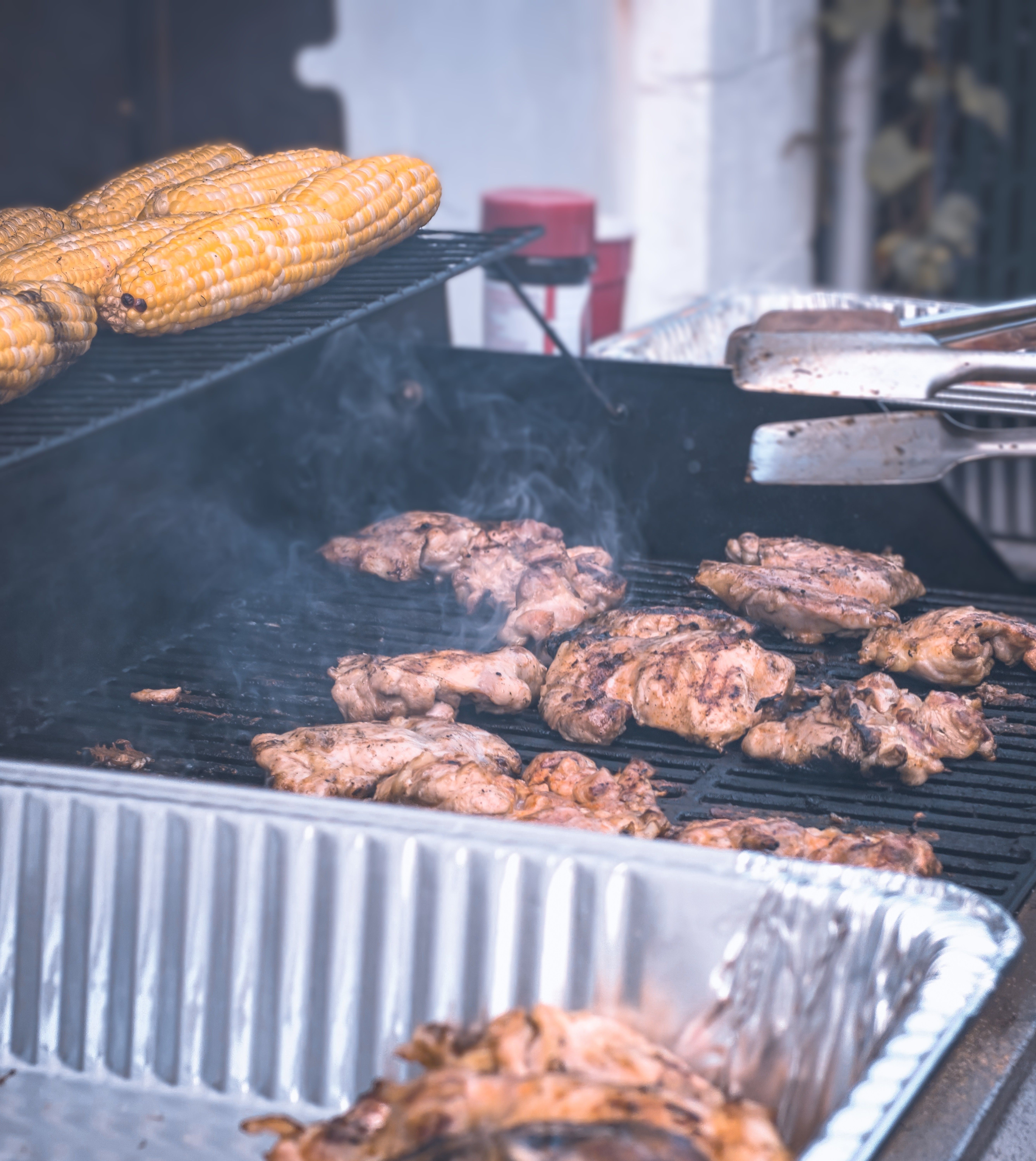 Juicy grilled meat and golden corn sizzling on a barbecue grill outdoors.